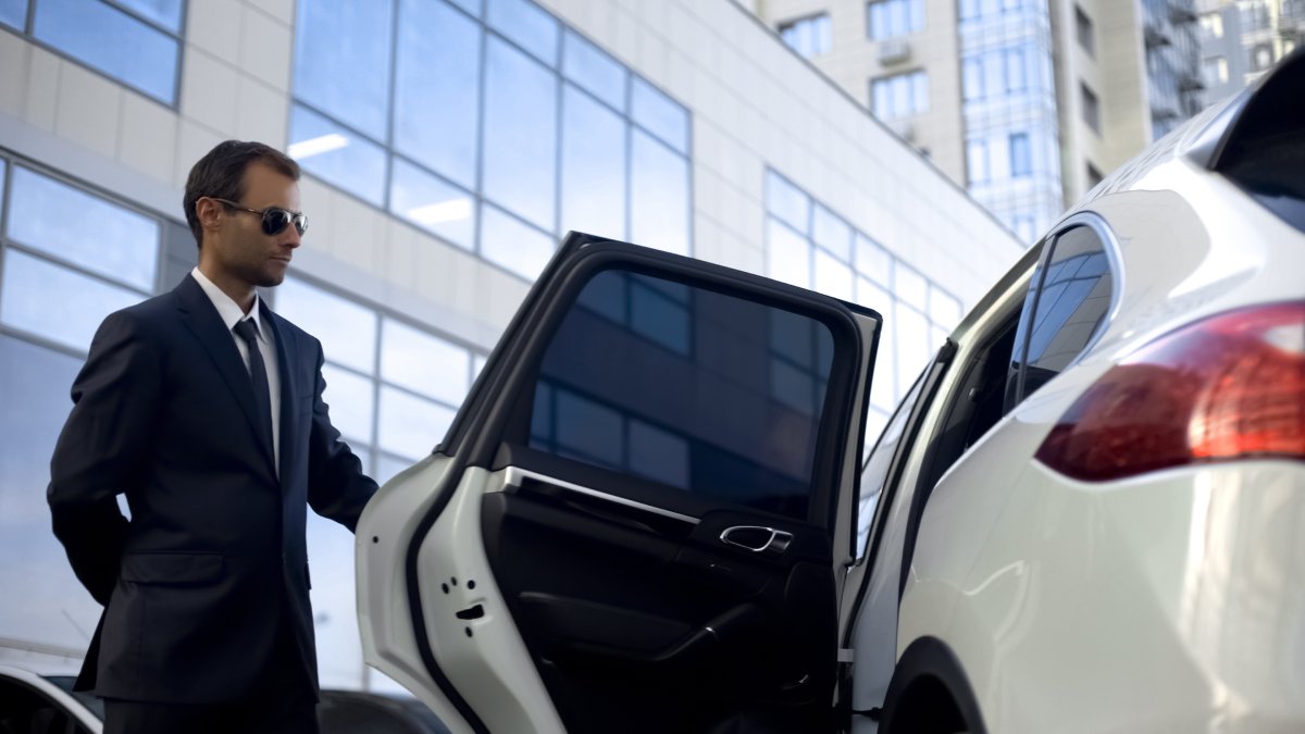 Personal driver opening white car door